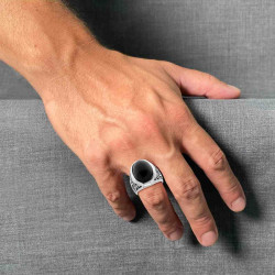 ANELLO CHEVALIER OVALE CON PIETRA BOMBATA NERA E DECORI LATERALI IN ACCIAIO BRUNITO